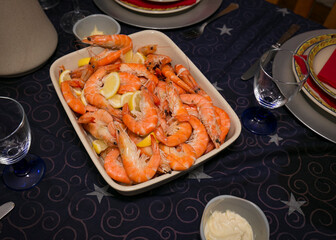 Detail of a platter with cooked shrimp on a dinner table.