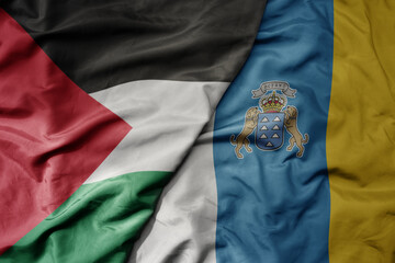 big waving national colorful flag of canary islands and national flag of palestine .