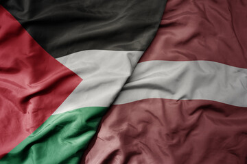 big waving national colorful flag of latvia and national flag of palestine .