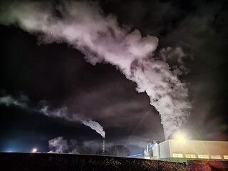Winter night industrial landscape. Coal-fired power station with smoking chimneys against dramatic...