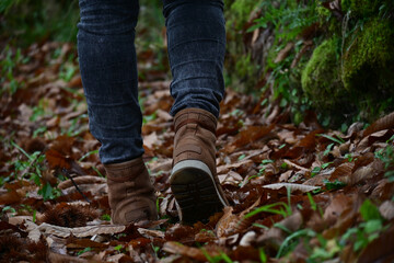 Detail of woman in hiking boots walking in a field in autumn