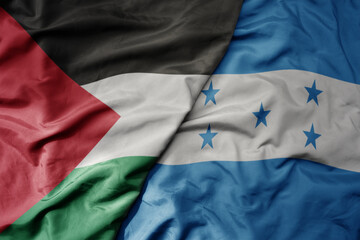 big waving national colorful flag of honduras and national flag of palestine .