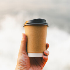 A man's hand holds a cup of coffee on a boat that runs on the sea.