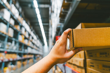 Cardboard box package with blur hand of Asian shopper woman picking product from shelf in...