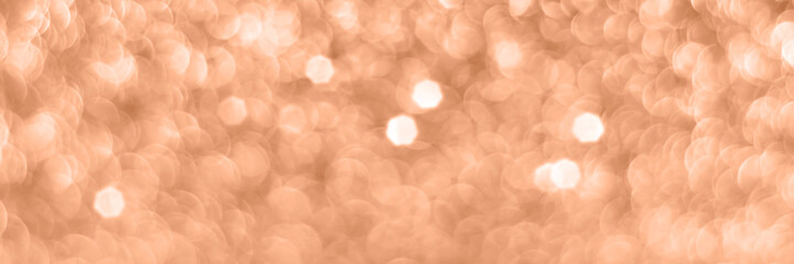 Peach fuzz sparkling glitter bokeh background banner, abstract panoramic defocused texture. Holiday...