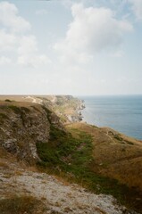 Fototapeta na wymiar rocky coast near the blue sea, on a sunny summer day with white clouds