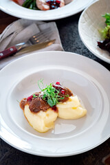 Mashed potatoes with goulash on a white plate. The dish is served with vegetables