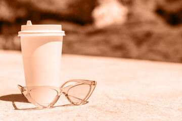 color of the year. Peach Fuzz. paper, plastic coffee cup, pink sunglasses. blurred background, sunny day. space for text, space for copy. word summer.