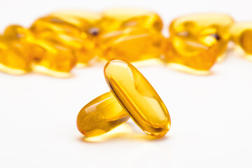 Fish oil softgel capsules scattered on a white table, focus on foreground