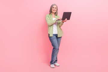 Full length photo of gorgeous cheerful pensioner lady wear stylish outfit use wireless netbook macbook isolated on pink color background