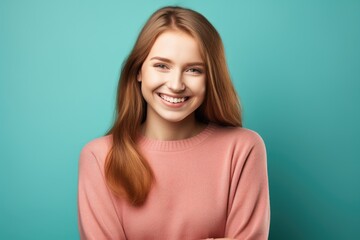 Fototapeta premium Happy caucasian young girl standing on light blue background. Smiling woman wearing warm peach sweater, winter fashion portrait. Cold season fashion. Sales and discount concept with copy space