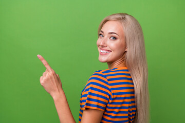 Profile side photo of adorable satisfied girl wear stylish clothes demonstrate empty space billboard isolated on green color background