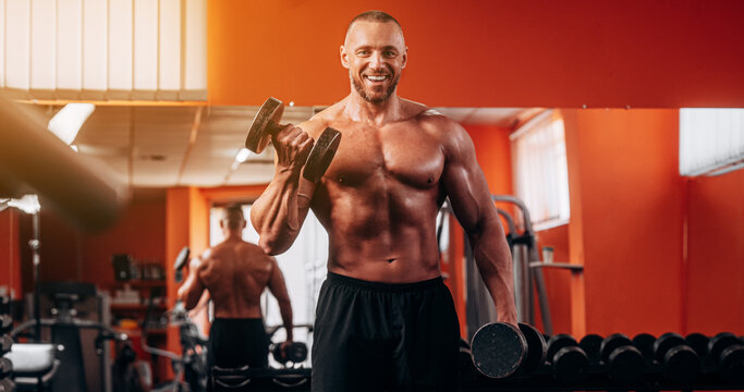 Portrait, dumbbells and man in gym smile while exercising. Sports workout, fitness and happy bodybuilder or athlete lifting weights for exercise, health and muscle.