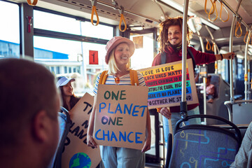 Happy young people holding climate change sign on the bus