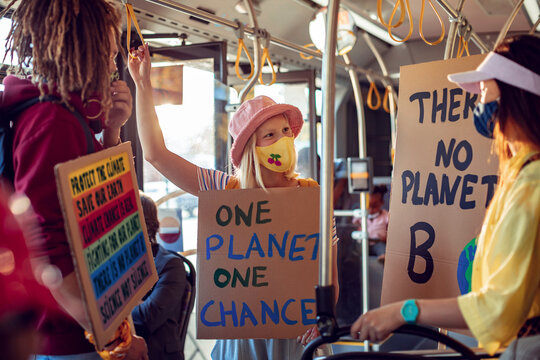 Happy young people holding climate change sign on the bus