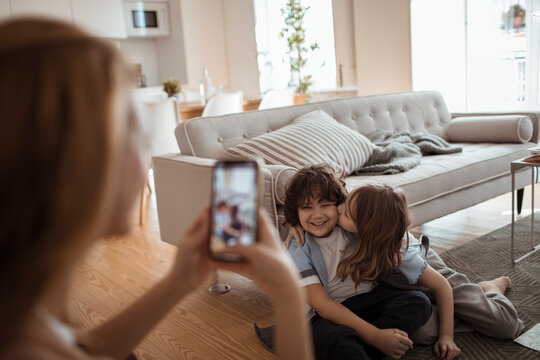 Mother taking smartphone picture of happy children at home