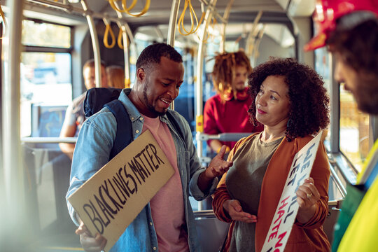 Young man and woman with anti racism signs on the bus