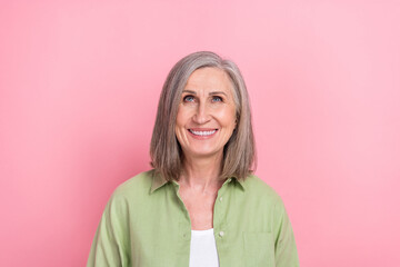 Fototapeta premium Portrait of retired woman grey hair wearing trendy khaki shirt looking above head useful information isolated on pink color background