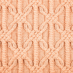 Knitted peach background. Large knitted fabric with a pattern. Close-up of a knitted blanket....