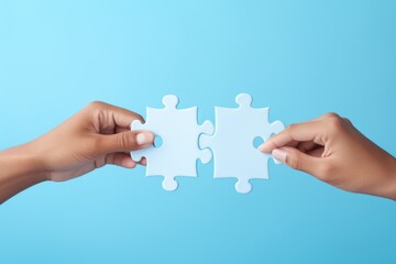 Two hands holding two pieces of a puzzle. Suitable for illustrating teamwork, problem-solving, collaboration, or completing a puzzle metaphorically - obrazy, fototapety, plakaty
