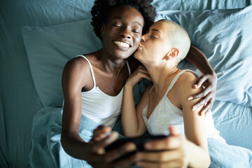 Loving lesbian couple taking selfie in bed