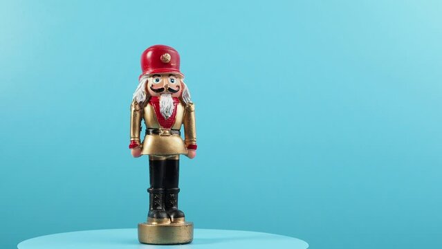 Rotating wooden figurine of the Nutcracker on a blue background. Christmas Nutcracker close-up.
