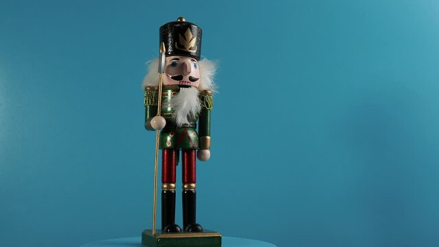 Rotating wooden figurine of the Nutcracker on a blue background. Christmas Nutcracker close-up.
