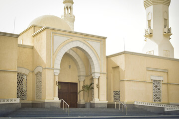 the beautiful exterior view of mosque with dome and minarets on sunny day