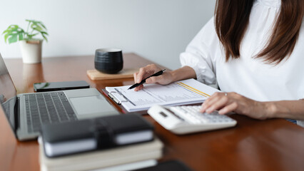 Writer woman calculate and check financial business document with calculator while working in cafe