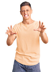 Young handsome man wearing casual clothes smiling funny doing claw gesture as cat, aggressive and...
