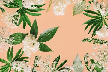 Assorted floral and jungle tree green leaves and white flowers frame border on peach pink. Natural sustainable environment friendly cosmetics mockup concept flat lay with copy space. Peach fuzz color