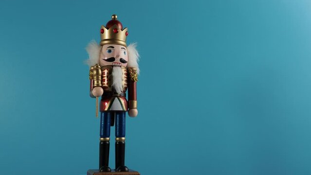 Rotating wooden figurine of the Nutcracker on a blue background. Christmas Nutcracker close-up.