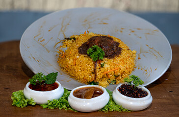 Fried rice with meat and vegetables on a wooden table. Restaurant