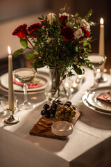 holidays, romantic date and celebration concept - close up of festive table serving for two with flowers in vase and candles burning at home on valentine's day