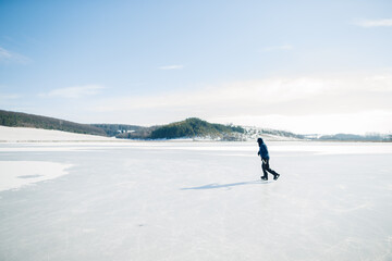 Fototapeta na wymiar Senior man on ice skates with hockey stick on frozen lake in winter. Hobby concept of elderly people.