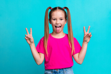 Portrait of small charming excited girl tongue out demonstrate v-sign isolated on emerald color...