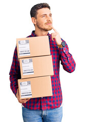 Handsome young man with bear holding delivery packages serious face thinking about question with...