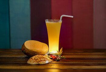 mango juice in a glass with a straw on a wooden table