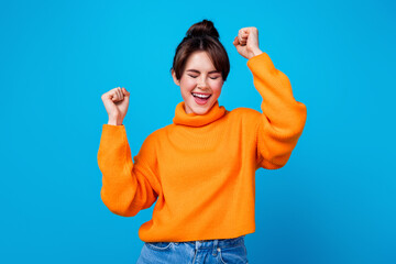 Photo of sweet lucky lady wear knitted pullover rising fist yelling yes closed eyes isolated blue...
