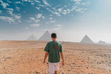 young man with a turban walks in the desert with the pyramids in the background. Cairo. Egypt
