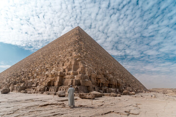 an Egyptian man with gray tunic at the base o Keops' pyramid. El Cairo . Egypt