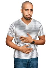 Hispanic adult man wearing casual clothes with hand on stomach because indigestion, painful illness feeling unwell. ache concept.