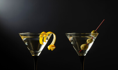 Classic dry martini cocktails with green olives and lemon peel on a black background.