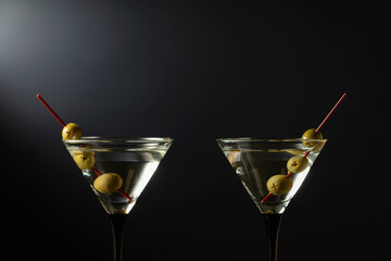 Glass of classic dry martini cocktail with lemon peel on a black background.