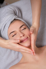 Fototapeta na wymiar Beautiful young woman getting facial massage in spa salon. Beauty treatment concept.