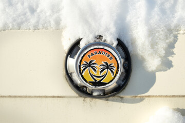 Snowed in car with summer holiday paradise sticker after an arctic snow storm. Funny close up...
