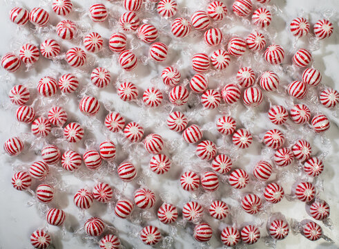 Round peppermint candies on white marble surface
