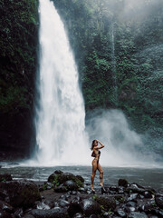 Obraz premium Gorgeous young woman in bikini posing near waterfall in Bali.