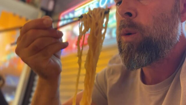 Mature man eating ramen noodles in the Japanese restaurant