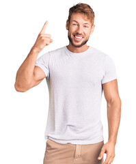 Naklejka premium Young caucasian man wearing casual white tshirt pointing finger up with successful idea. exited and happy. number one.